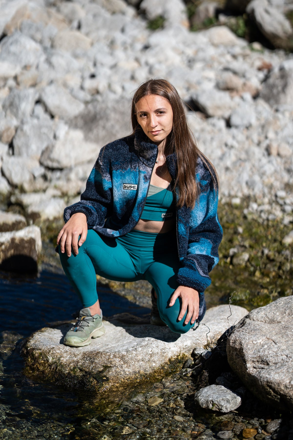 FW26-028 BEAR Arctic Sunrise + Kaleido River + Leggings vita alta Ottanio (donna accovacciata sul torrente)